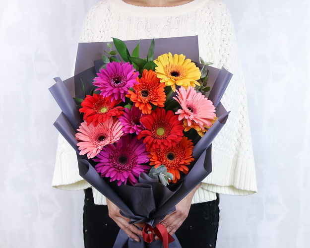 Букет з 11 Гербер стандарт мікс у стильній упаковці із зеленню