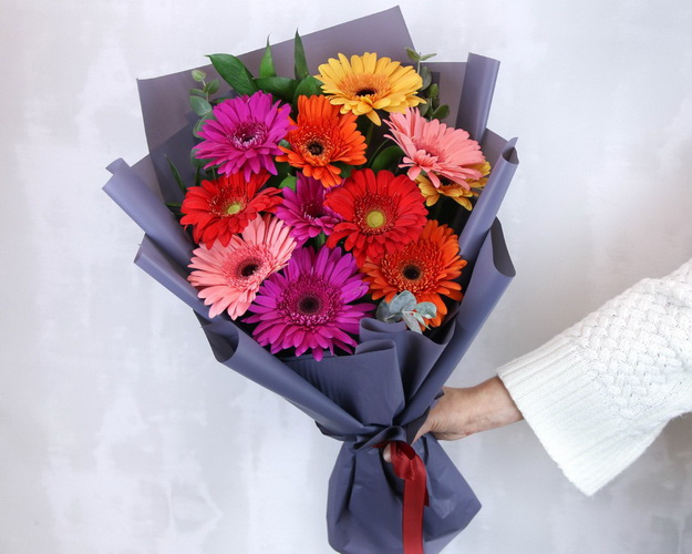 Букет з 11 Гербер стандарт мікс у стильній упаковці із зеленню