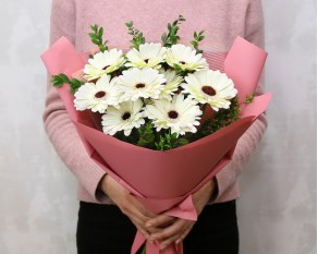 Букет із 9 білих міні гербер у стильній упаковці із зеленню