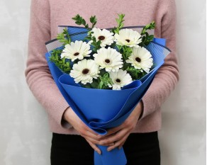 Букет із 7 білих міні гербер у стильній упаковці із зеленню