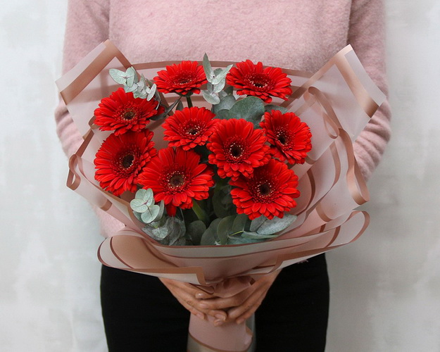 Букет із 9 червоних міні гербер у стильній упаковці із зеленню