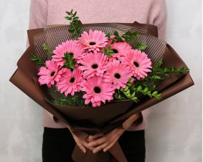 Букет із 9 рожевих міні гербер у стильній упаковці із зеленню