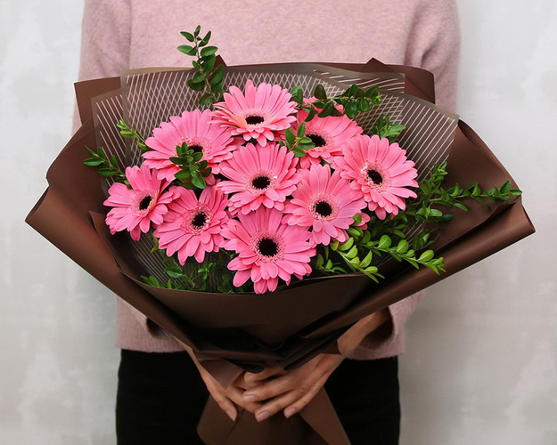 Букет із 9 рожевих міні гербер у стильній упаковці із зеленню