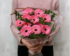 Букет із 11 рожевих міні гербер у стильній упаковці із зеленню