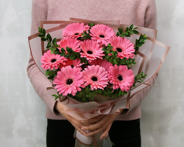 Букет із 11 рожевих міні гербер у стильній упаковці із зеленню