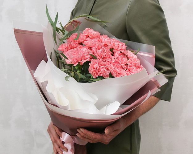 Букет із 15 рожевих гвоздик у стильній упаковці із зеленню