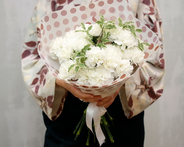 Букет із 25 білих гвоздик із зеленню в стильній упаковці.