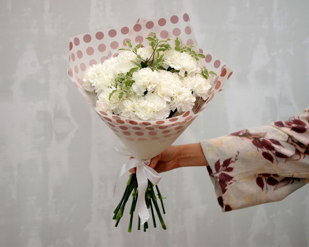 Букет із 25 білих гвоздик із зеленню в стильній упаковці.