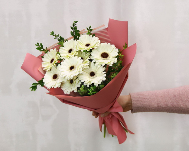 Букет із 9 білих міні гербер у стильній упаковці із зеленню