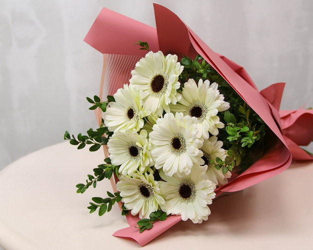 Букет із 9 білих міні гербер у стильній упаковці із зеленню