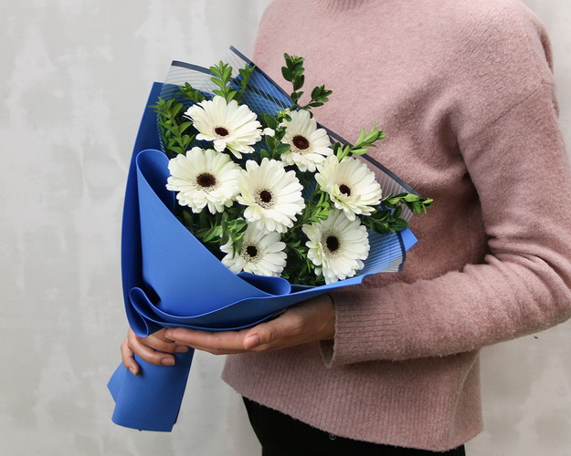 Букет із 7 білих міні гербер у стильній упаковці із зеленню