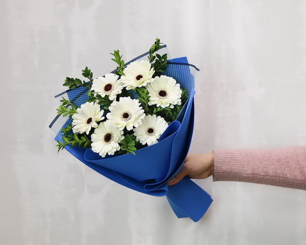 Букет із 7 білих міні гербер у стильній упаковці із зеленню