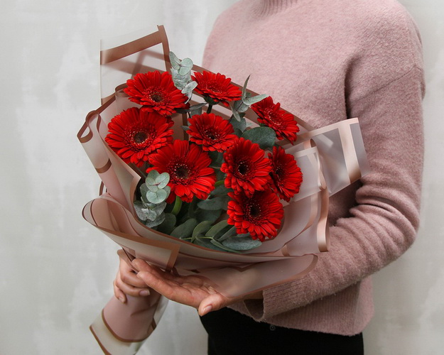 Букет із 9 червоних міні гербер у стильній упаковці із зеленню