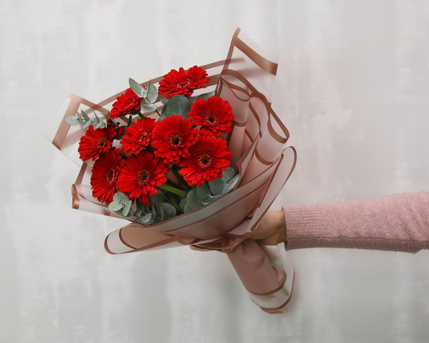 Букет із 9 червоних міні гербер у стильній упаковці із зеленню