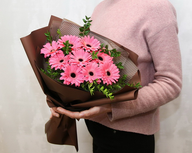 Букет із 9 рожевих міні гербер у стильній упаковці із зеленню