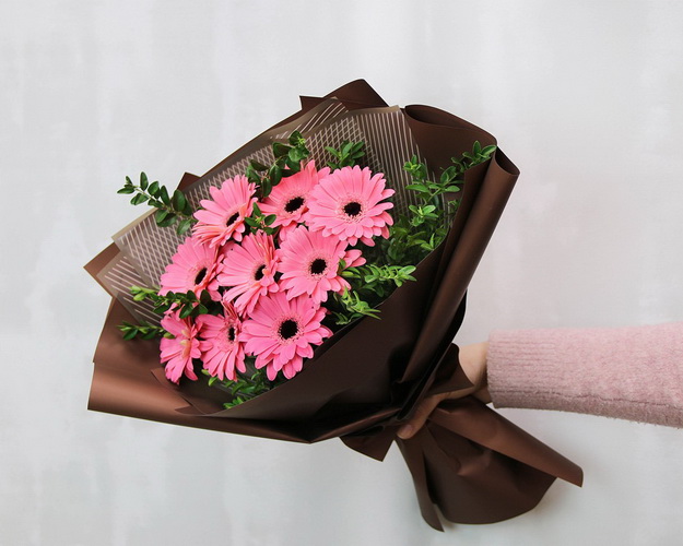 Букет із 9 рожевих міні гербер у стильній упаковці із зеленню
