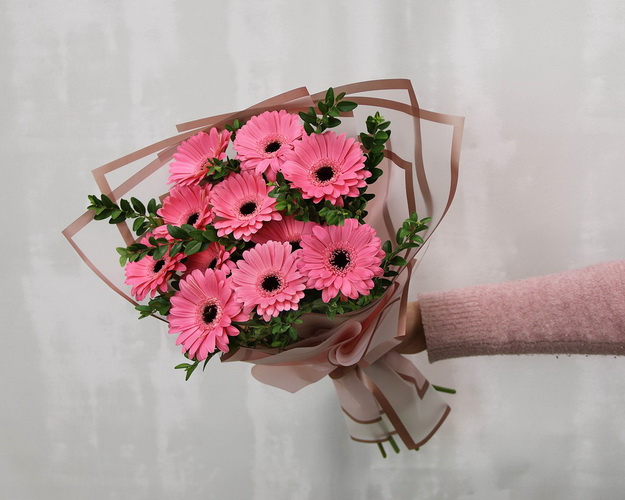 Букет із 11 рожевих міні гербер у стильній упаковці із зеленню