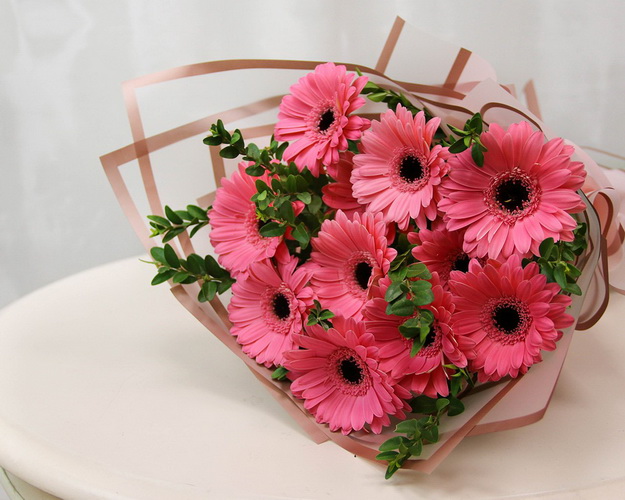 Букет із 11 рожевих міні гербер у стильній упаковці із зеленню