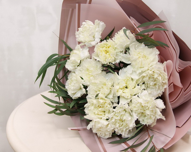 Букет із 15 білих гвоздик у стильній упаковці із зеленню