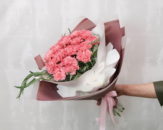 Букет із 15 рожевих гвоздик у стильній упаковці із зеленню