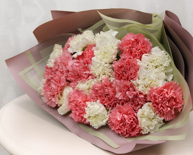 Букет із 25 рожевих та білих гвоздик у стильній упаковці.