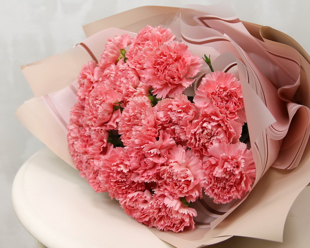 Букет із 25 рожевих гвоздик у стильній упаковці.